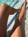 Young womanÃ¢â¬â¢s long tan legs in bright blue pool water